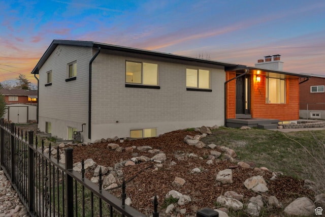 exterior space featuring a chimney, fence, and brick siding