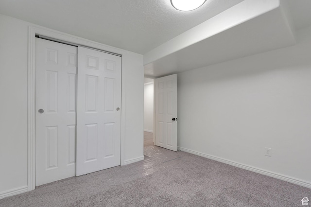 unfurnished bedroom featuring baseboards, carpet flooring, a textured ceiling, and a closet