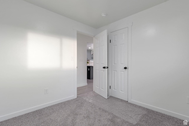 spare room featuring light carpet and baseboards