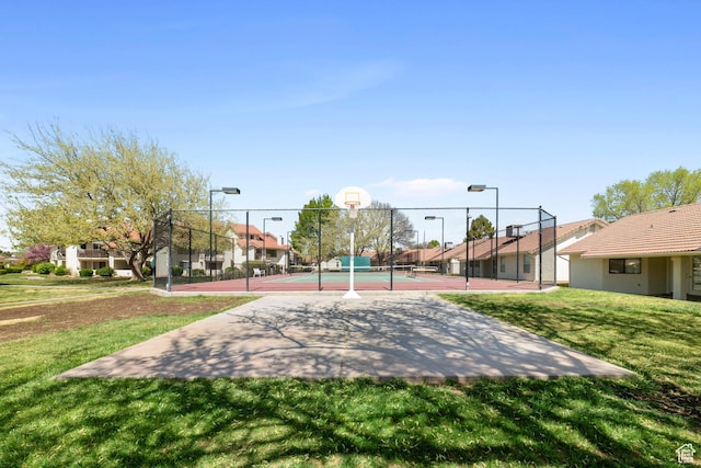 view of sport court featuring a tennis court, community basketball court, fence, a residential view, and a yard