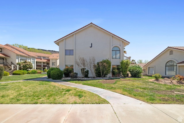 view of home's exterior featuring a tiled roof, stucco siding, and a lawn