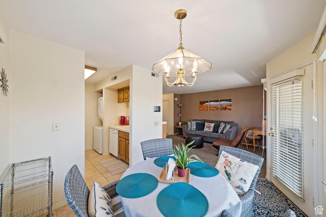 dining space with an inviting chandelier, light tile patterned floors, separate washer and dryer, and visible vents