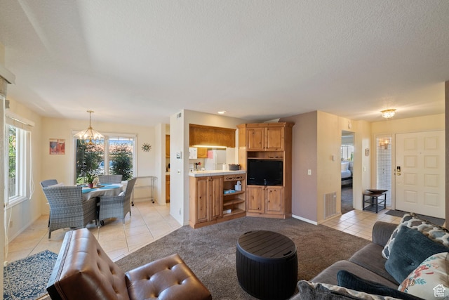living room featuring a textured ceiling, an inviting chandelier, light tile patterned floors, and light colored carpet