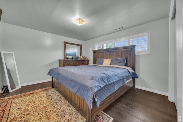 bedroom with baseboards, visible vents, and wood finished floors