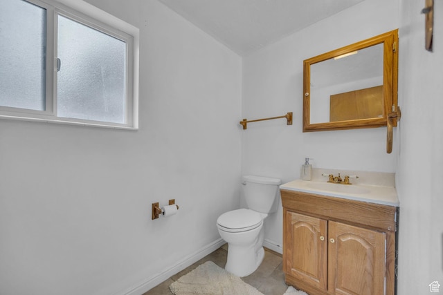 half bathroom featuring baseboards, toilet, and vanity