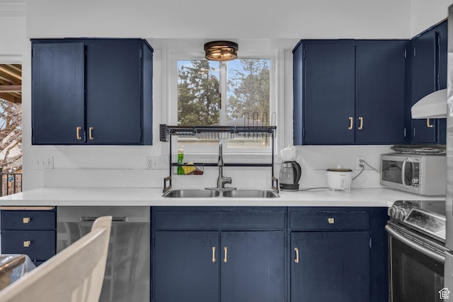 kitchen with blue cabinetry, light countertops, a sink, and appliances with stainless steel finishes