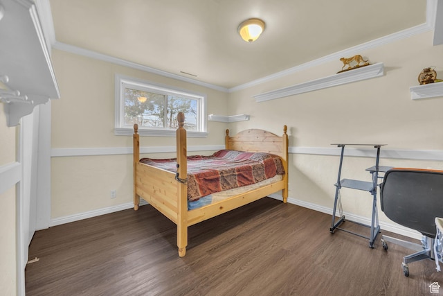 bedroom with baseboards, crown molding, and wood finished floors