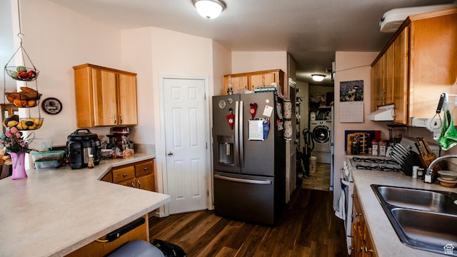 kitchen featuring range with gas stovetop, dark wood-type flooring, under cabinet range hood, a sink, and stainless steel refrigerator with ice dispenser