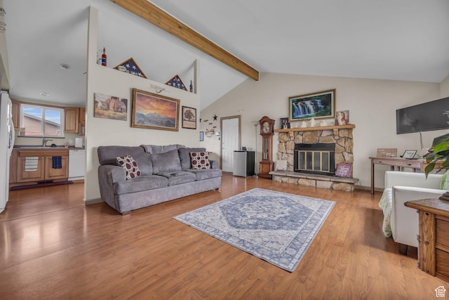 living area featuring high vaulted ceiling, beam ceiling, a fireplace, and light wood-type flooring