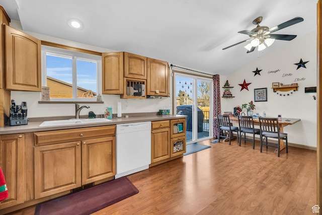 kitchen with a sink, white dishwasher, light wood-style floors, and lofted ceiling