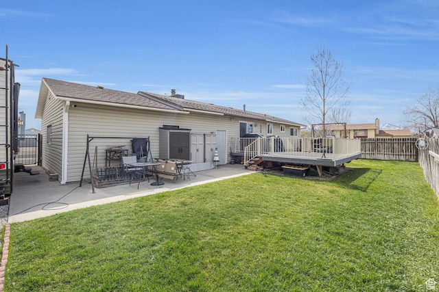 rear view of property with a fenced backyard, a lawn, a wooden deck, and a patio
