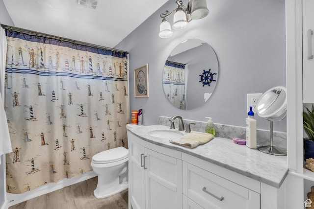full bath with visible vents, a shower with shower curtain, toilet, wood finished floors, and vanity