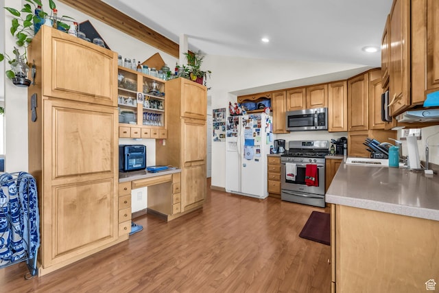 kitchen featuring light wood finished floors, built in desk, stainless steel appliances, a sink, and vaulted ceiling