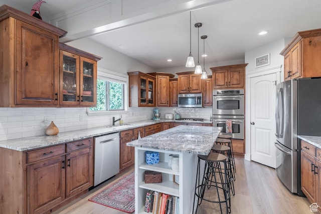 1255 W 3300 N, Pleasant View, UT 84414 - kitchen featuring brown cabinets, stainless steel appliances, a sink, a breakfast bar area, and backsplash