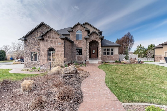 view of front facade featuring a front yard, fence, and brick siding