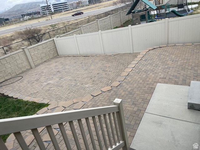 view of patio / terrace with a playground, a mountain view, and fence