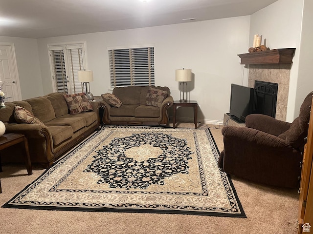 living area with light carpet, baseboards, and a tiled fireplace
