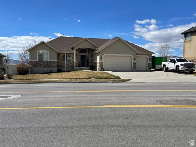 ranch-style house featuring stone siding, an attached garage, concrete driveway, and stucco siding