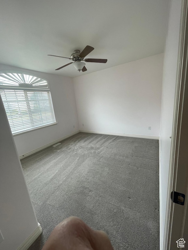 spare room featuring baseboards, carpet flooring, and a ceiling fan