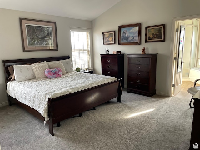 bedroom featuring light colored carpet, connected bathroom, baseboards, and vaulted ceiling