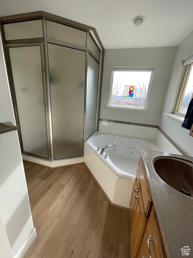 full bathroom with vanity, wood finished floors, a tub with jets, and a shower stall