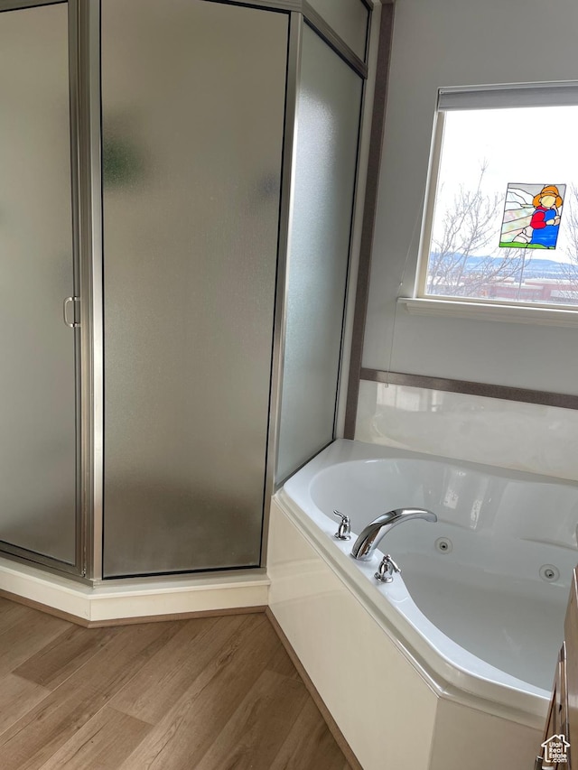 full bath featuring a shower stall, a jetted tub, and wood finished floors