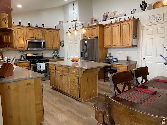 kitchen with light wood finished floors, brown cabinets, a center island, and appliances with stainless steel finishes