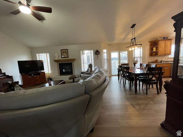living area with vaulted ceiling, light wood-style floors, and ceiling fan
