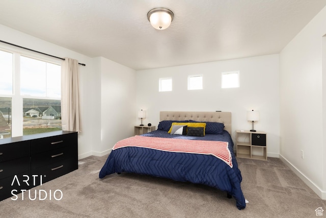 bedroom with baseboards and light carpet