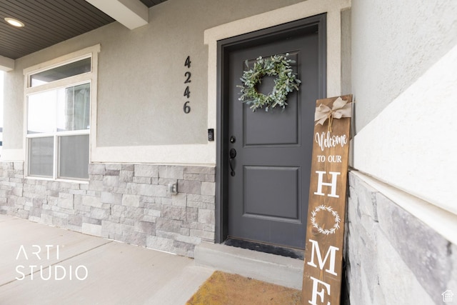 doorway to property featuring stone siding and stucco siding