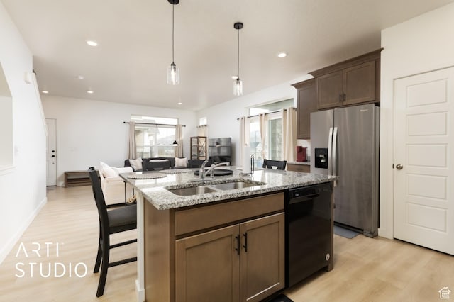kitchen with a kitchen island with sink, black dishwasher, a sink, stainless steel refrigerator with ice dispenser, and light wood-type flooring