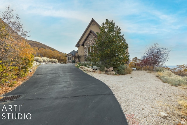 5055 Waterfall Dr, Pleasant View, UT 84414 - view of side of home with stone siding and aphalt driveway
