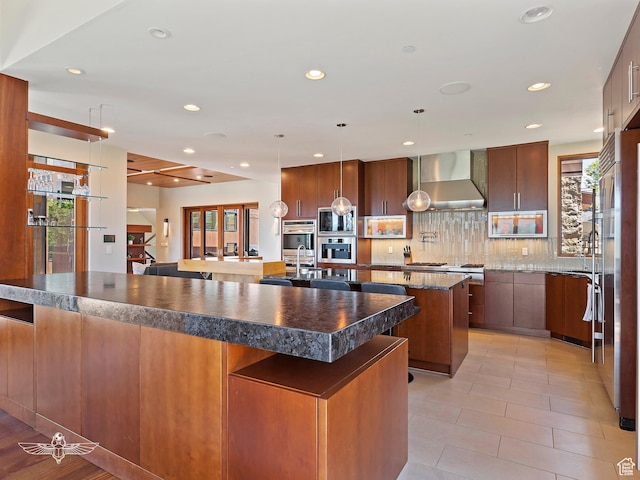 6639 E Chaparral Rd, Huntsville, UT 84317 - kitchen with a large island with sink, dark countertops, a breakfast bar, and wall chimney exhaust hood