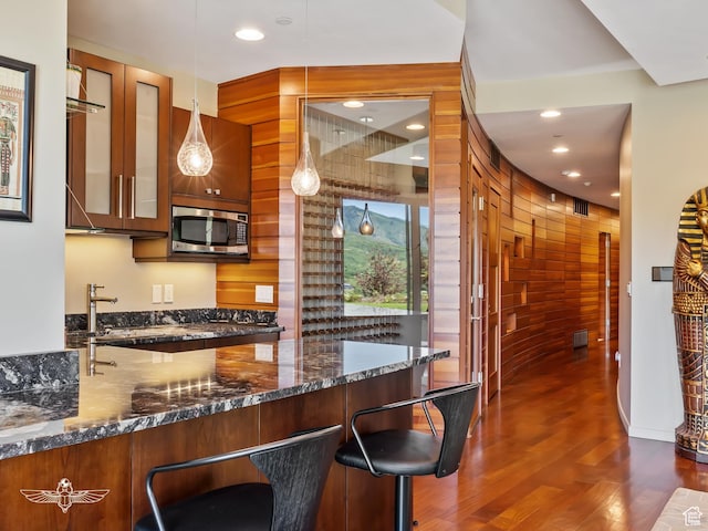 6639 E Chaparral Rd, Huntsville, UT 84317 - kitchen featuring wood walls, stainless steel microwave, dark wood-type flooring, glass insert cabinets, and decorative light fixtures