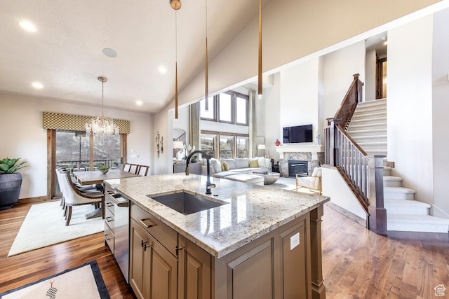kitchen featuring dark wood-style flooring, a sink, a notable chandelier, and a stone fireplace