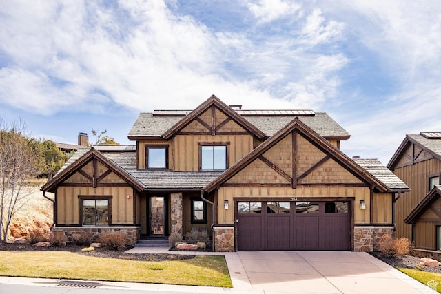 view of front facade featuring solar panels, a garage, concrete driveway, and stone siding