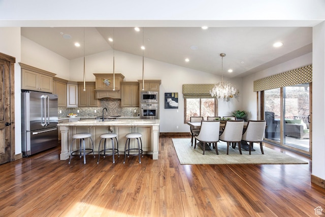 kitchen with an island with sink, tasteful backsplash, a breakfast bar, appliances with stainless steel finishes, and dark wood finished floors