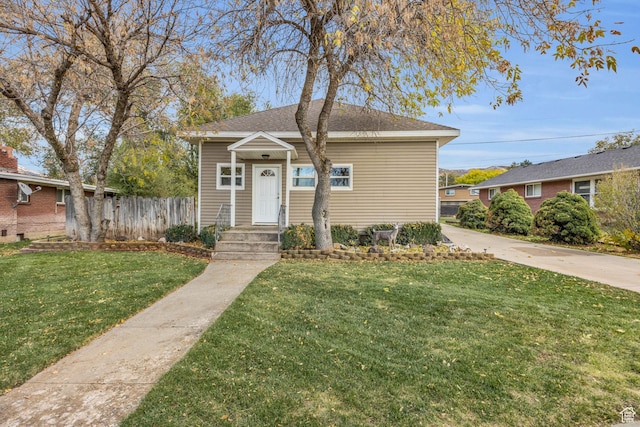 bungalow with roof with shingles, fence, and a front lawn