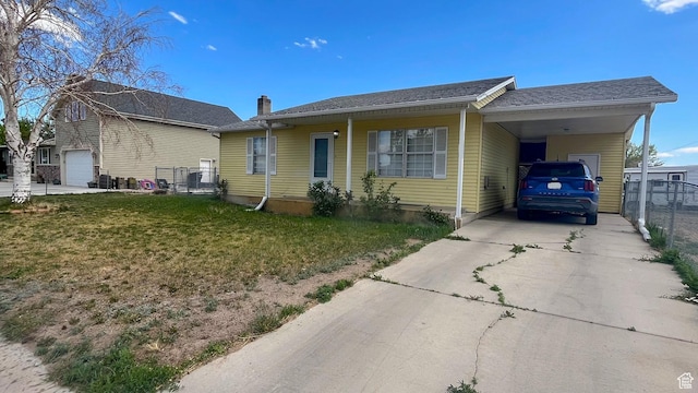 view of front facade with fence, a chimney, a front yard, an attached carport, and driveway