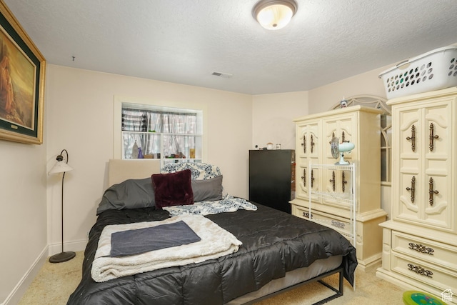 bedroom featuring a textured ceiling, baseboards, light colored carpet, and visible vents