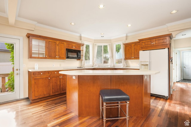 kitchen with black microwave, light countertops, a center island, and white fridge with ice dispenser
