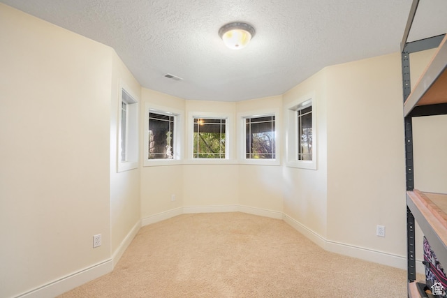 spare room featuring carpet, baseboards, a textured ceiling, and visible vents