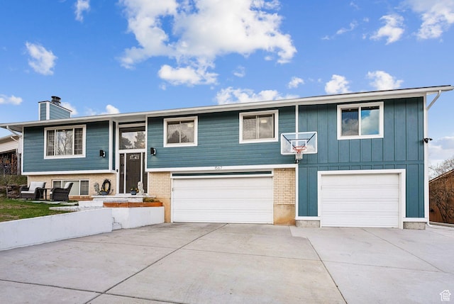 1567 Heather Dr, Layton, UT 84040 - split foyer home featuring a chimney, concrete driveway, board and batten siding, and an attached garage