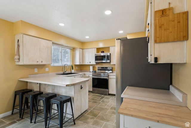 1567 Heather Dr, Layton, UT 84040 - kitchen featuring light countertops, a peninsula, a kitchen bar, stainless steel appliances, and a sink
