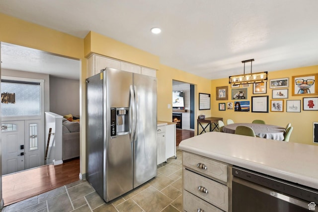 1567 Heather Dr, Layton, UT 84040 - kitchen featuring light countertops, a lit fireplace, hanging light fixtures, white cabinets, and appliances with stainless steel finishes