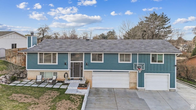 raised ranch with board and batten siding, driveway, and an attached garage