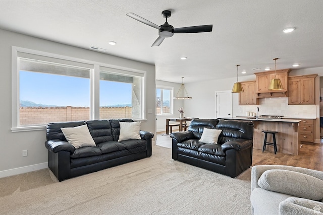 carpeted living area featuring a textured ceiling, visible vents, baseboards, ceiling fan, and recessed lighting