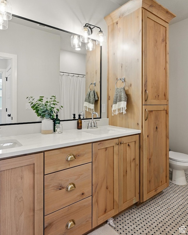 bathroom with double vanity, a sink, and toilet