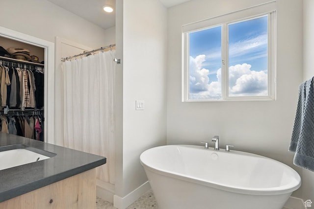 full bathroom featuring a shower with shower curtain, baseboards, vanity, a freestanding bath, and a spacious closet