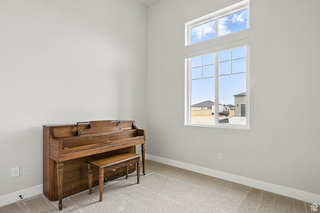living area featuring light carpet and baseboards